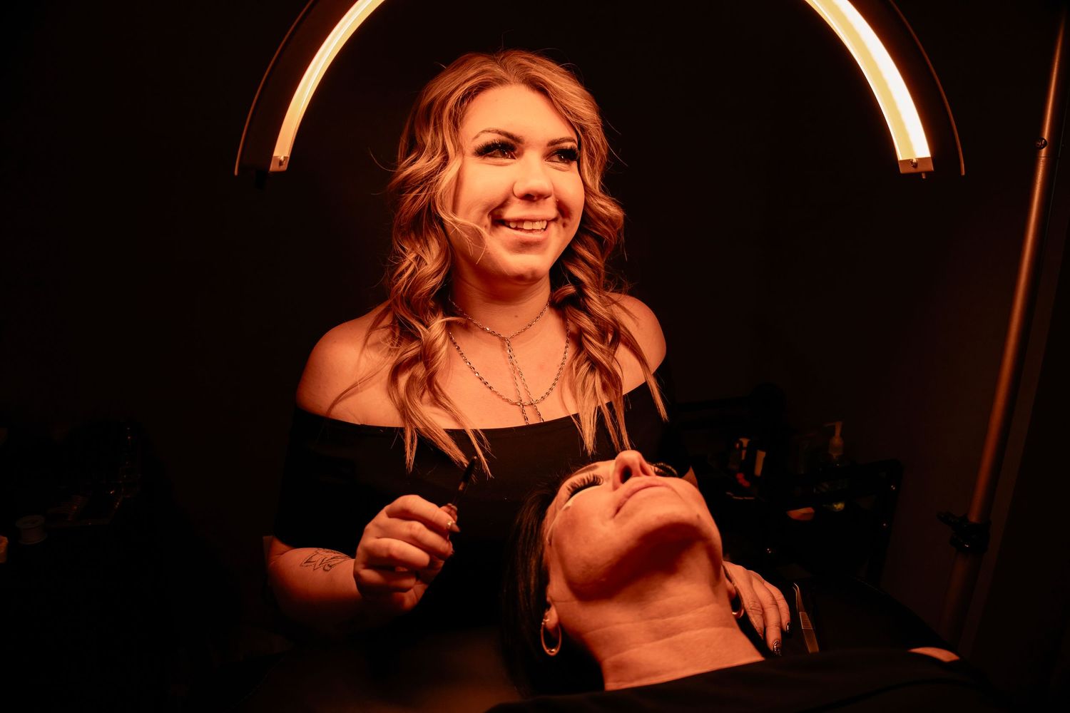 Professional eyelash extension procedure being performed in ambient lighting conditions.