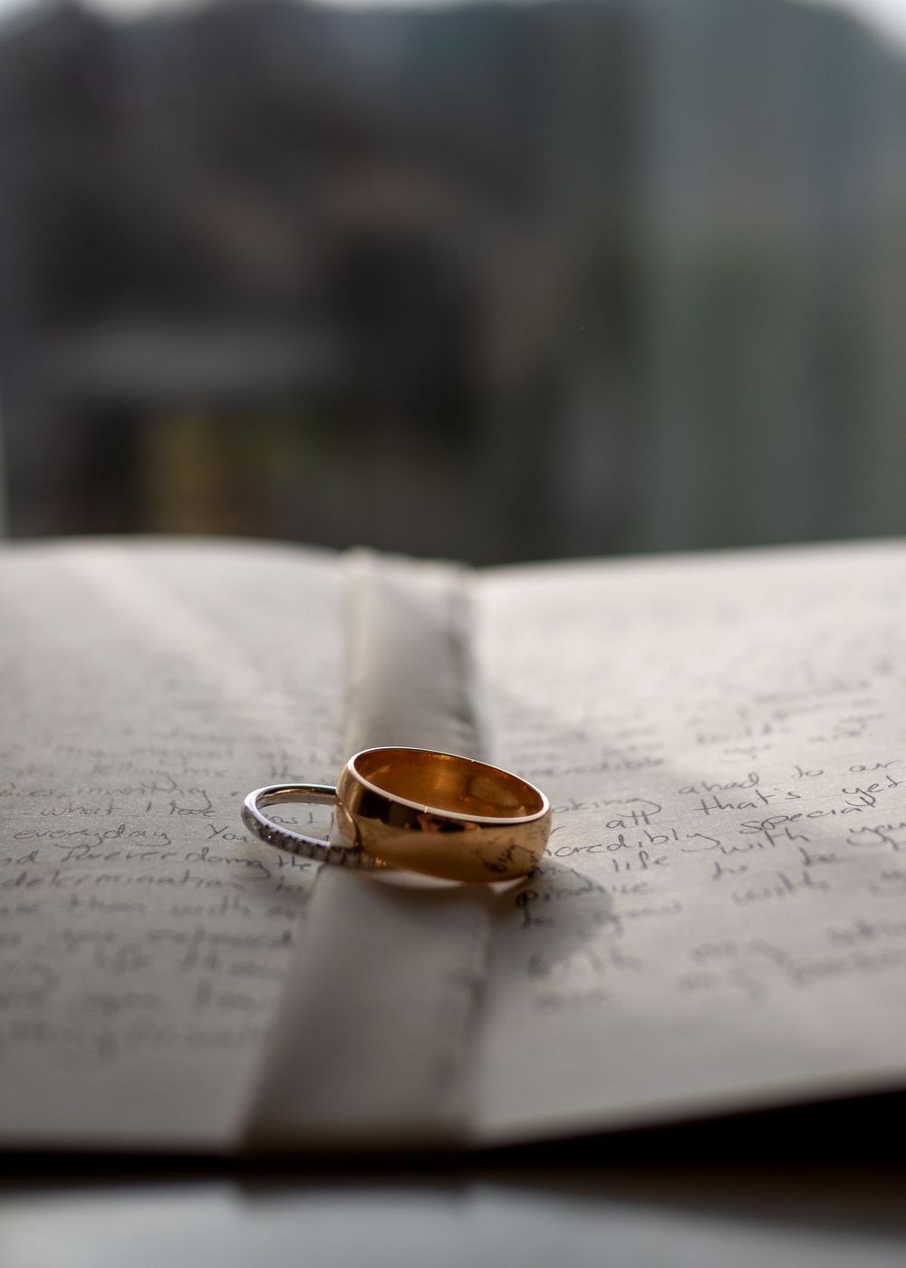 Two wedding rings resting on an open book with handwritten text.