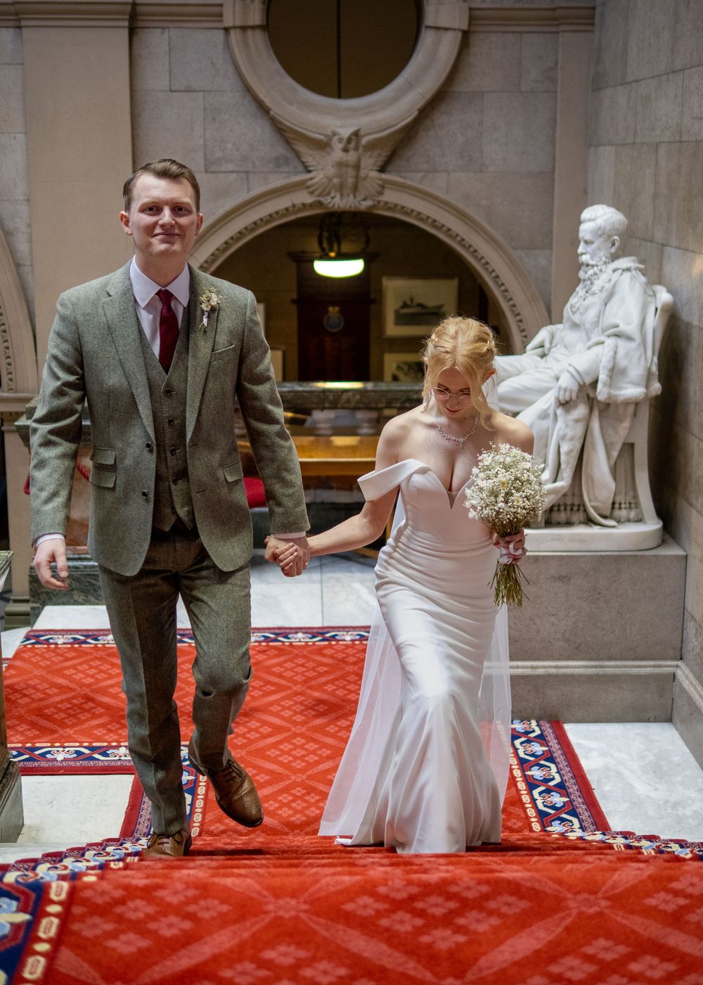 Sheffield Town Hall Wedding - Wedding couple walking down red carpet in grand hallway with architectural details.