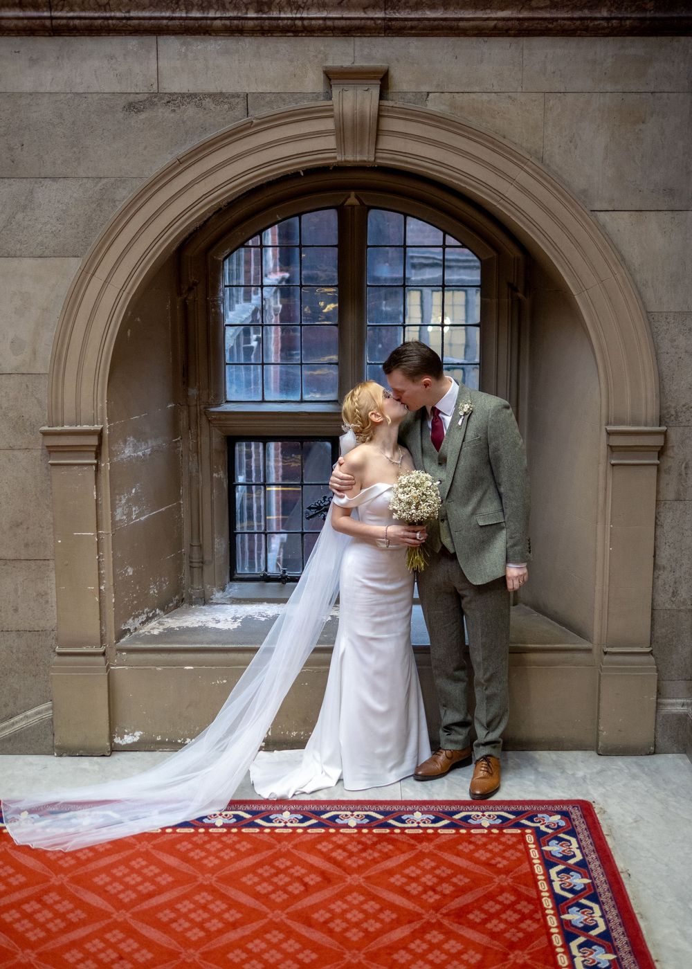 Sheffield Town Hall Wedding - Romantic wedding portrait under stone archway with red patterned carpet.