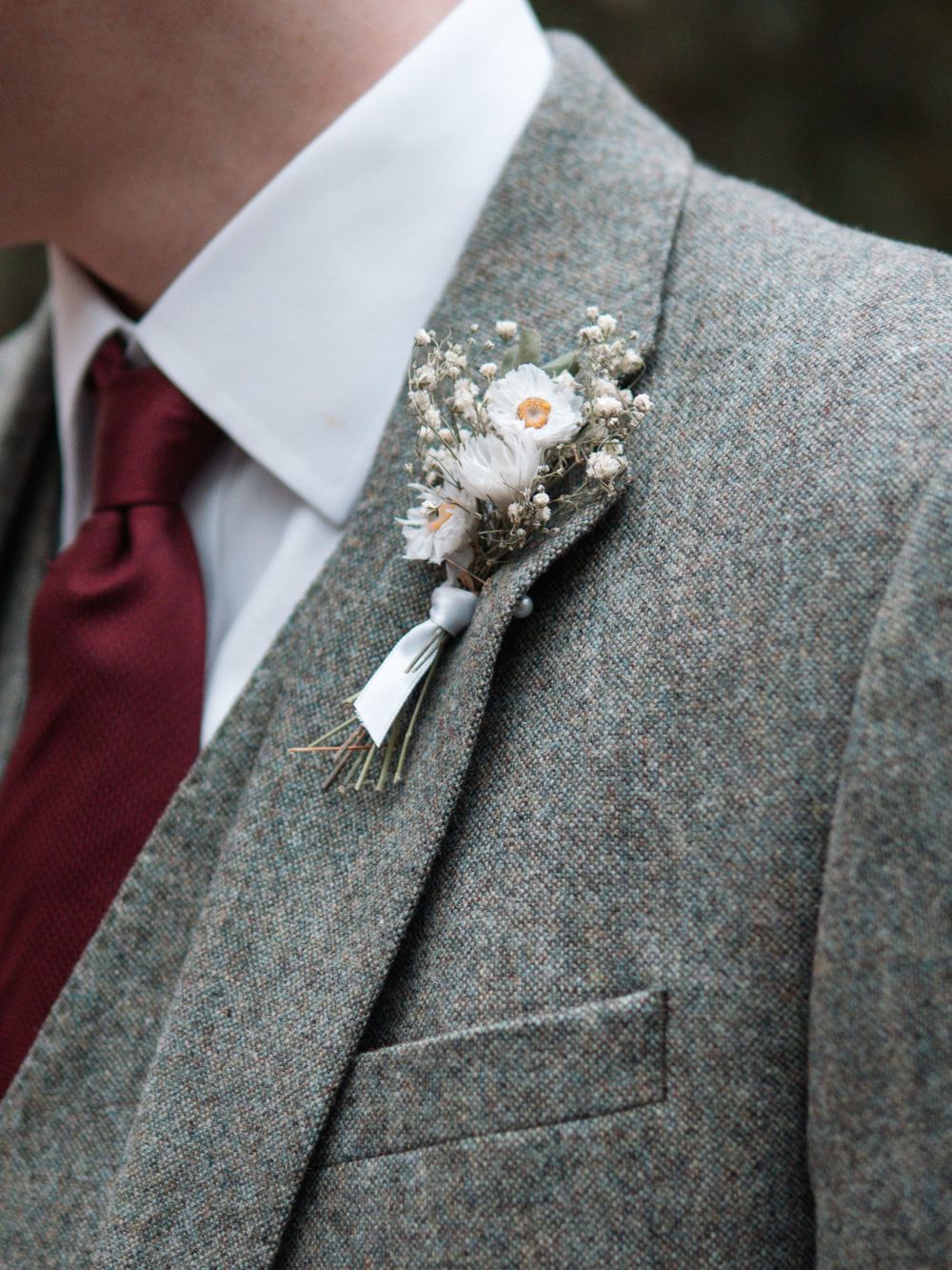Sheffield Town Hall Wedding - Close-up detail of a grey tweed suit jacket with burgundy tie and delicate white floral boutonniere.
