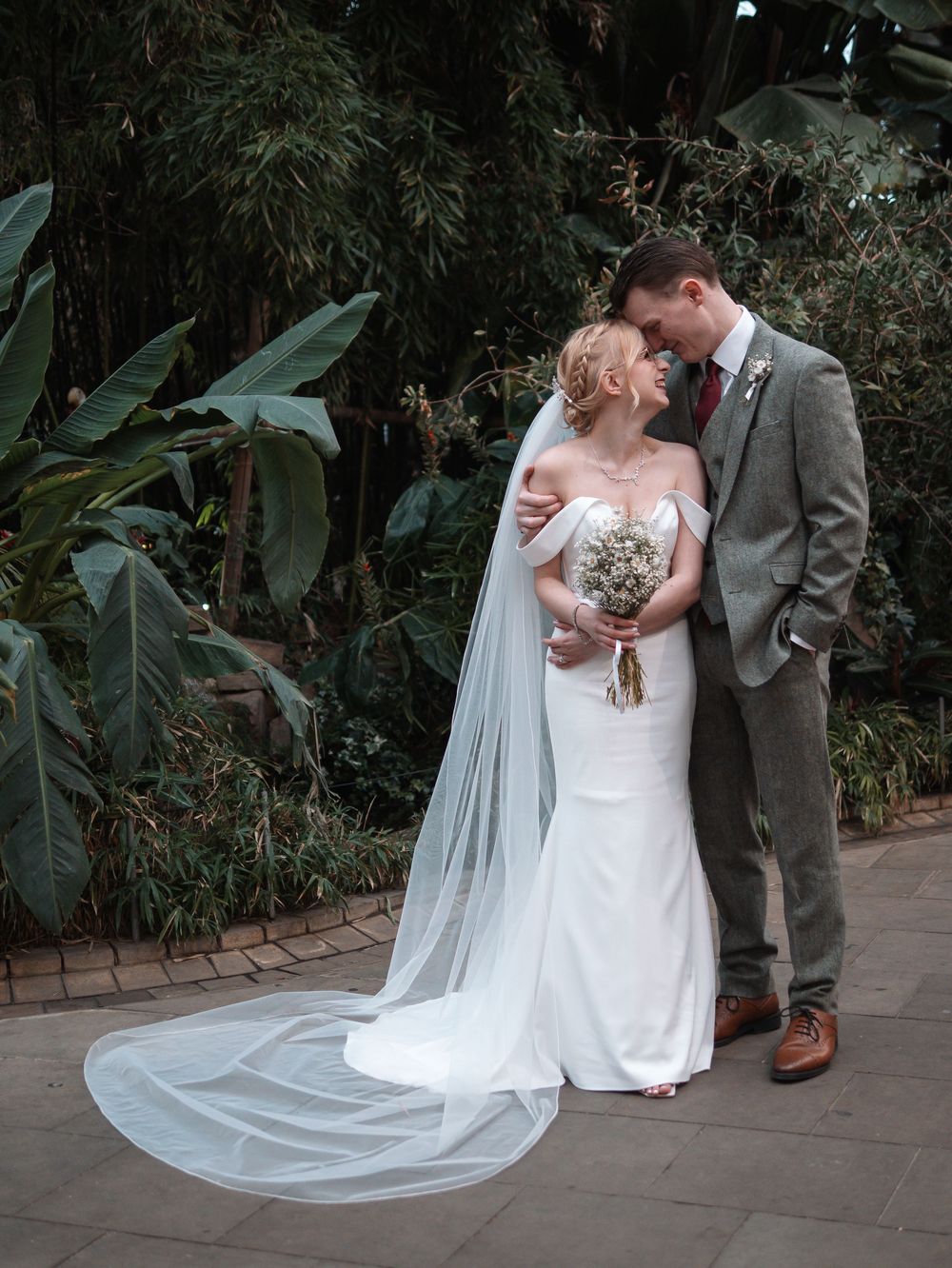 Sheffield Town Hall Wedding -  Elegant wedding couple poses outdoors with flowing white veil against lush greenery.