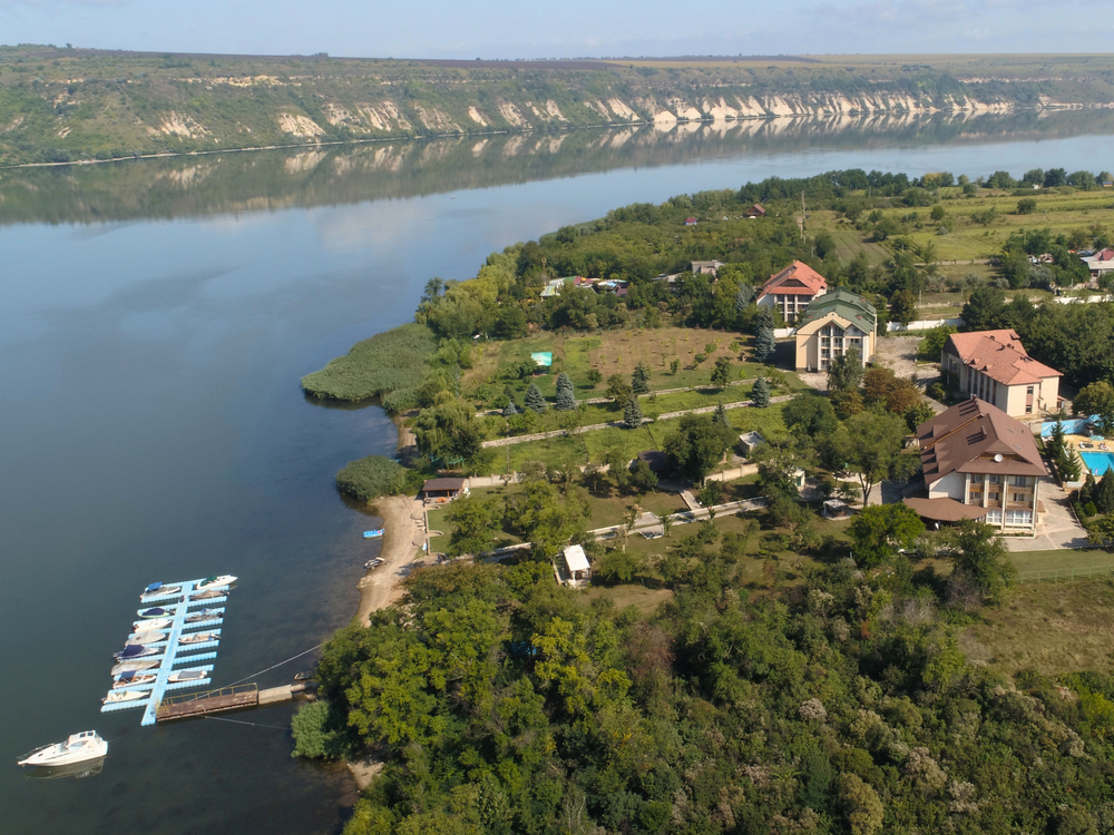 Aerial view of a peaceful riverside property with a boat dock surrounded by green trees.