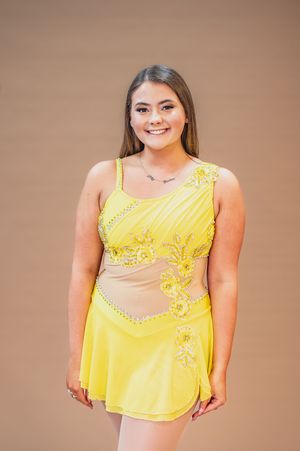 Dancer poses in yellow performance costume with intricate beaded details.