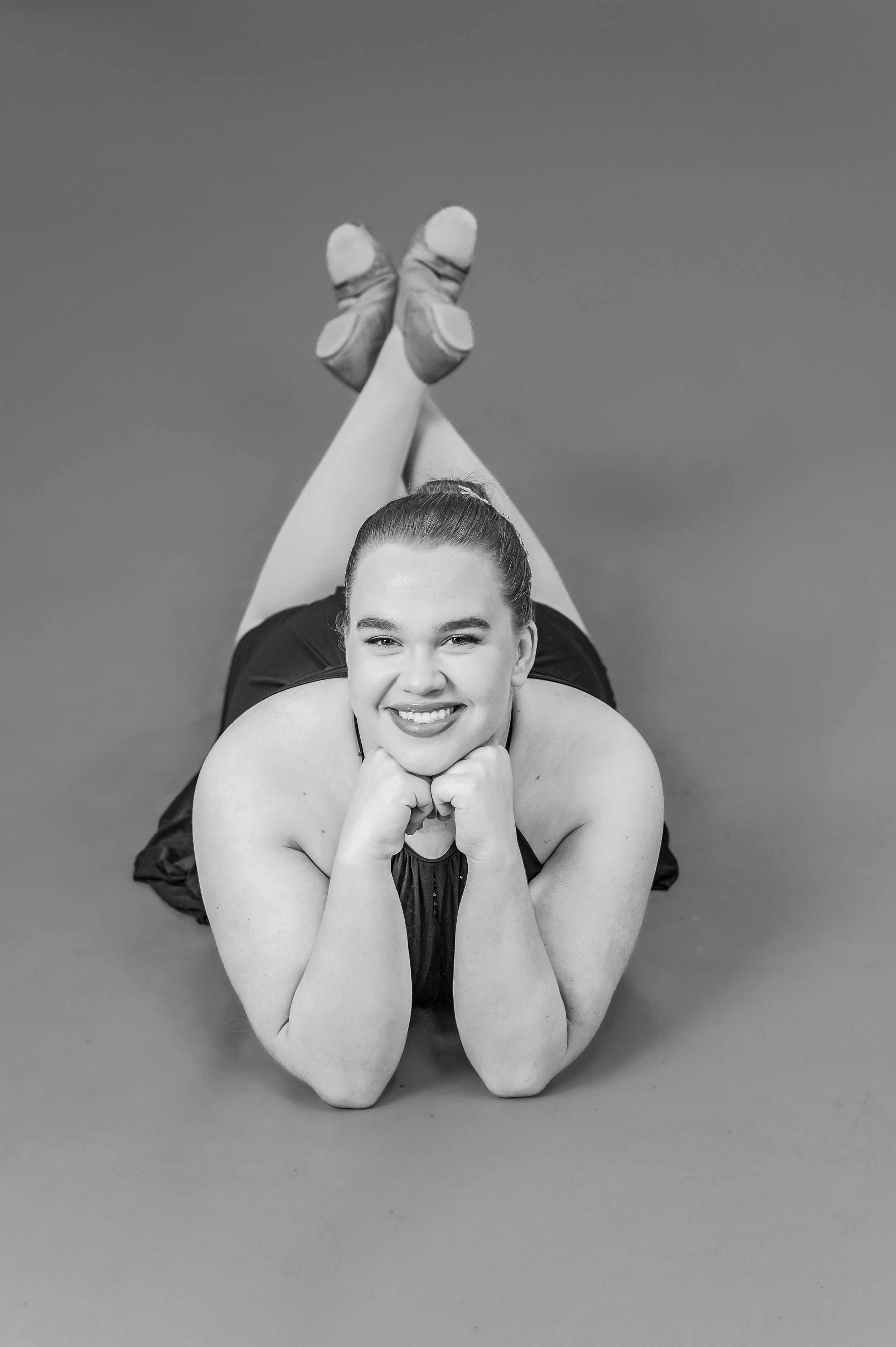 Black and white portrait of dancer lying down in ballet shoes with crossed feet.