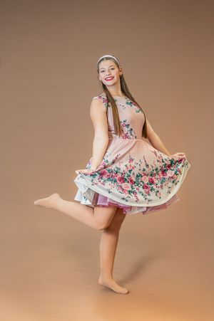 Dancer twirls in floral print dress showing flowing movement against neutral background.