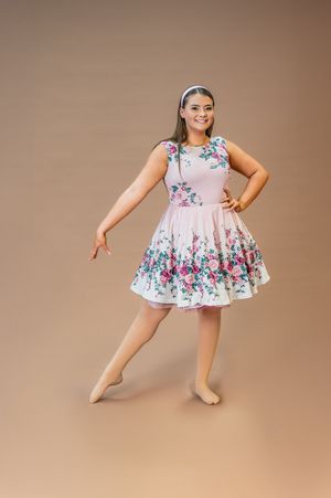 Dancer poses elegantly in pink floral dress with flared skirt.