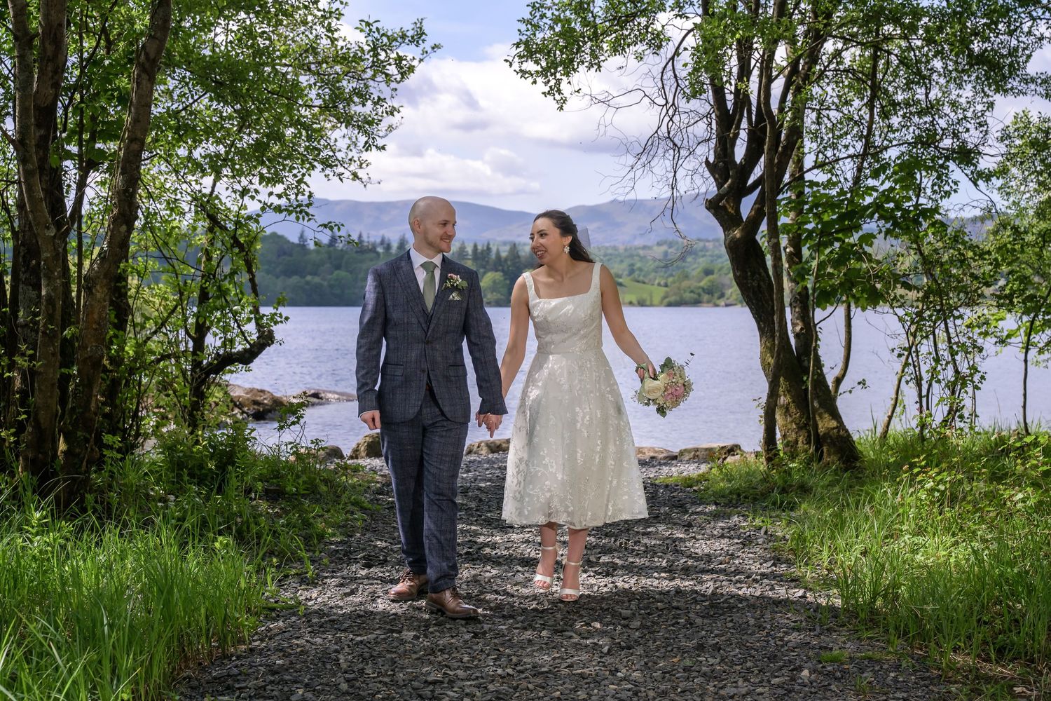 Bride and groom walking together under trees beside Windermere at Cragwood Country House