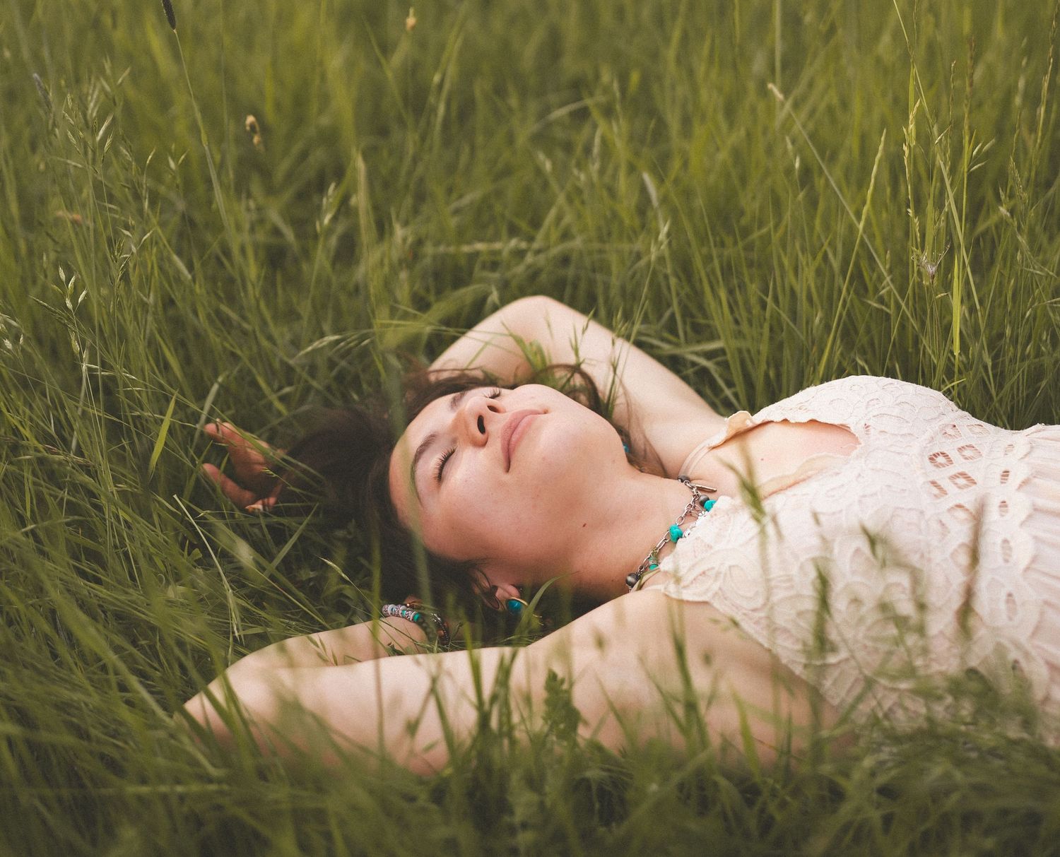 Person lying in tall grass during golden hour photography session.