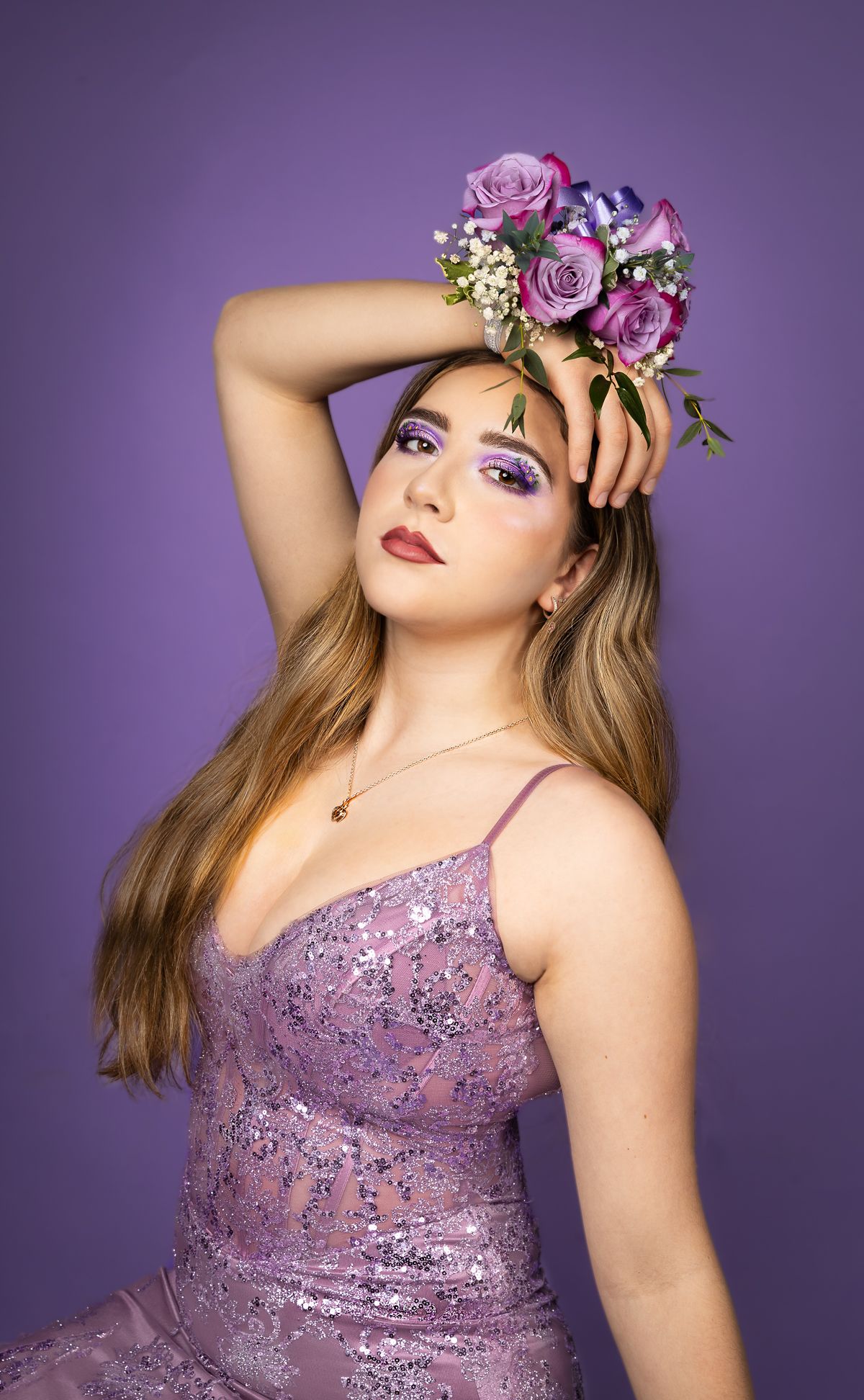 Girl with purple makeup and corsage in front of a purple backdrop
