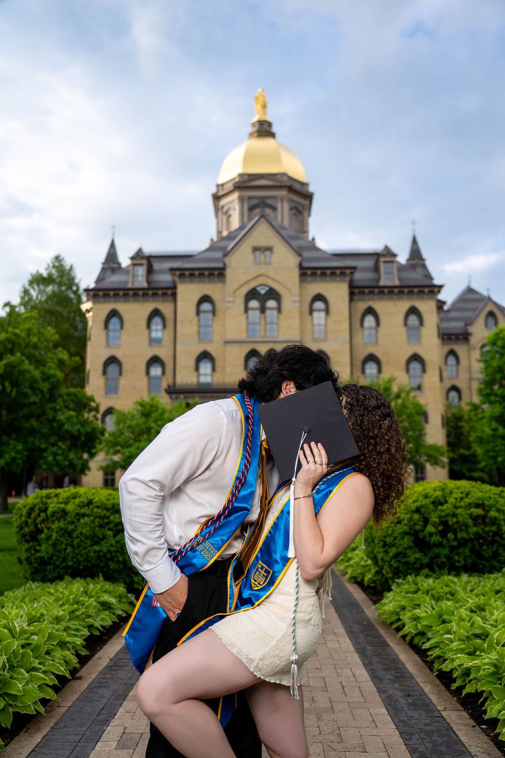 Scenic university photoshoot at Notre Dame featuring the iconic golden dome and Gothic architecture in the background.