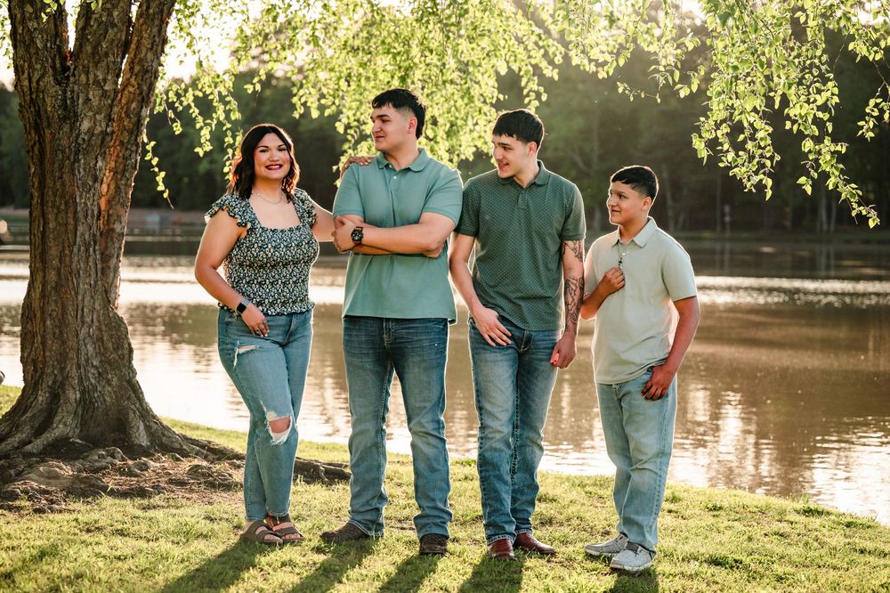 A family enjoying a sunny afternoon walk together by a serene pond in a park.