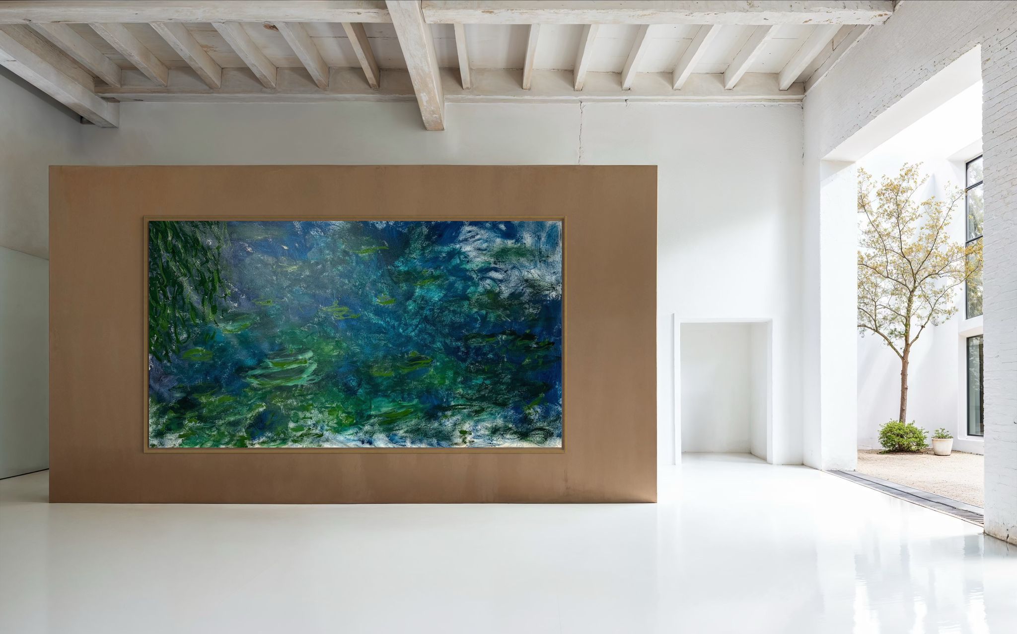 Large aquarium with vibrant blue water installed in a modern white room with exposed beams and minimalist decor.