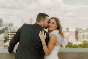 Romantic couple embraces on a rooftop terrace with urban skyline in the background during golden hour.