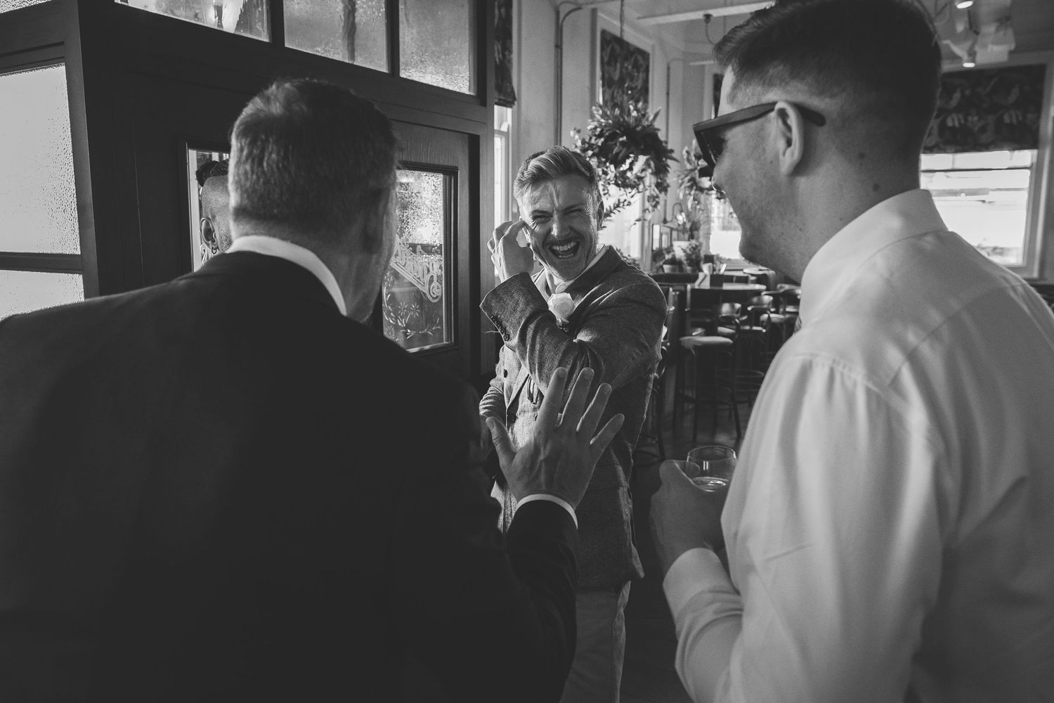 A group of well-dressed guests share laughter and drinks at an elegant reception party.