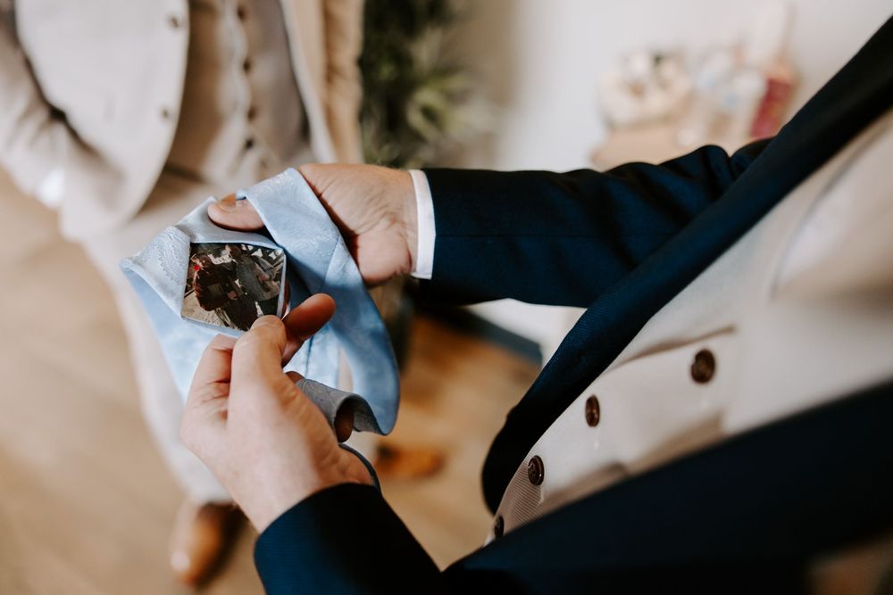 Close up of hands adjusting a timepiece or watch while wearing a formal navy suit.