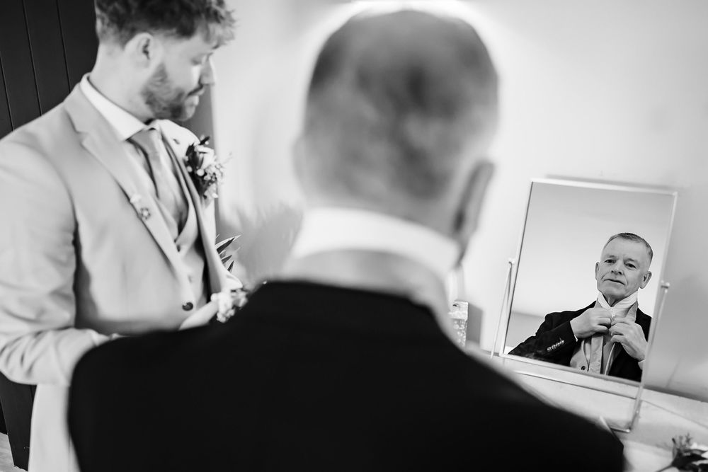 Wedding party preparation scene captured in black and white shows candid interactions and joyful moments.