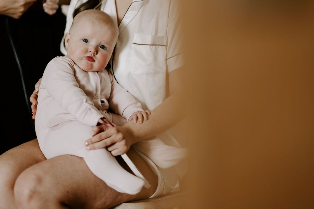 Sepia-toned photo series of a precious baby in white clothing being held and cradled during a lifestyle photoshoot.