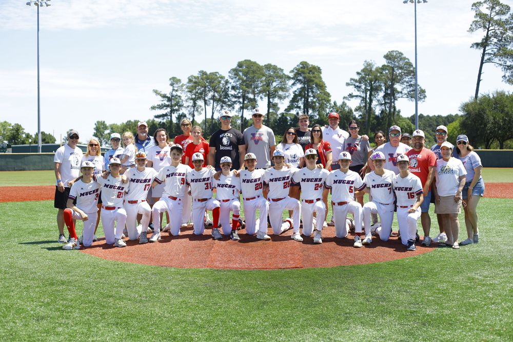 Youth baseball team and coaches pose for group photo on baseball field.