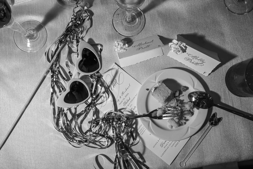 Aerial view of computer desk setup with laptop, notebooks, headphone cables, and various digital accessories in black and white.