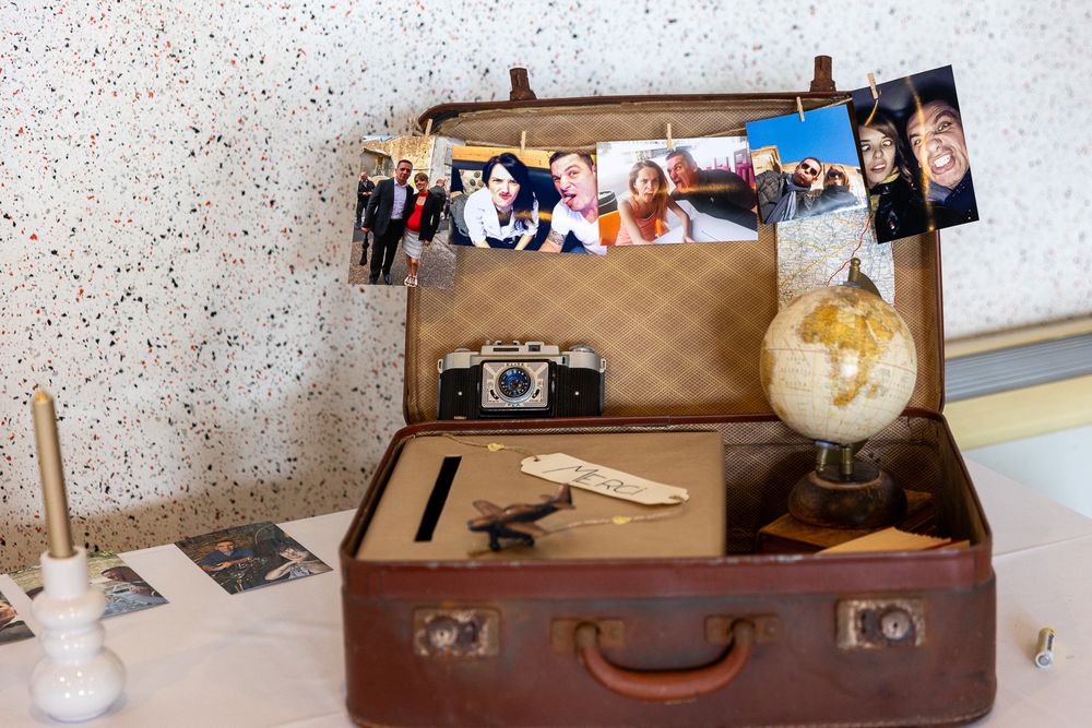 Vintage suitcase display with photos, camera and decorative globe creating nostalgic wedding decor.