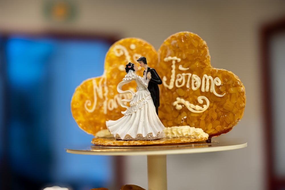A decorative wedding cake topper featuring a golden heart with Je t'aime text and ornate designs.