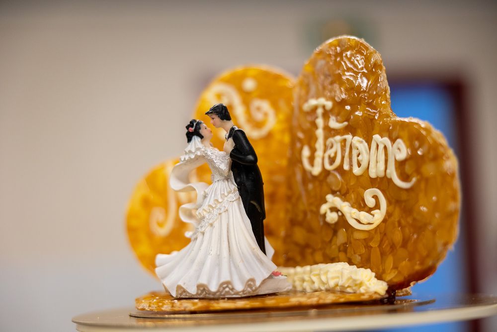 Wedding cake topper with golden heart and Je t'aime inscription displayed on a pedestal.