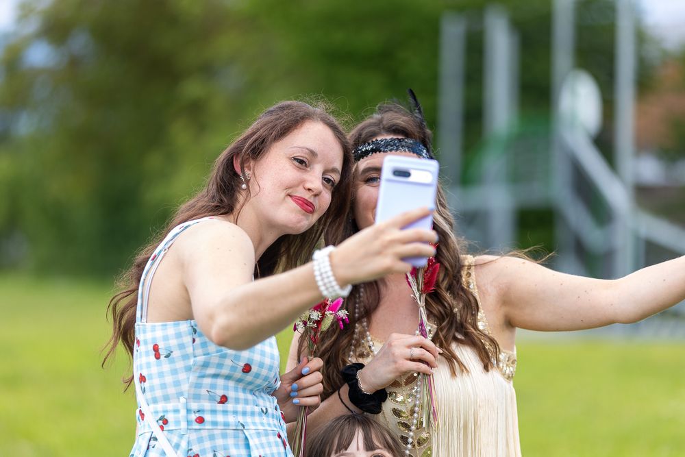 Friends taking selfie photos together at an outdoor summer party.