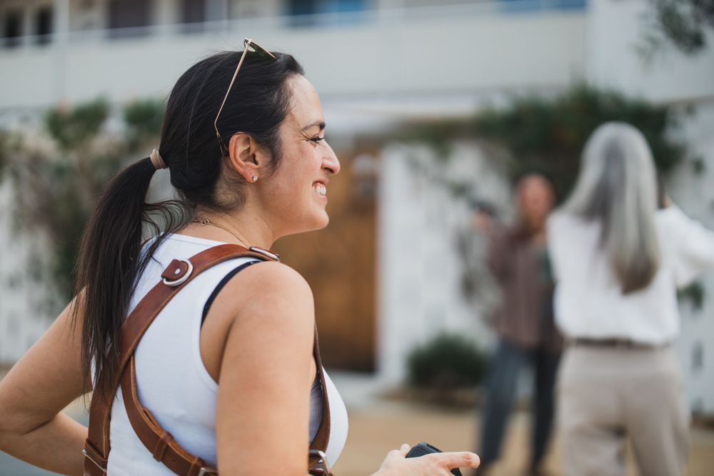 A photographer with a camera stands in profile view against a blurred background.