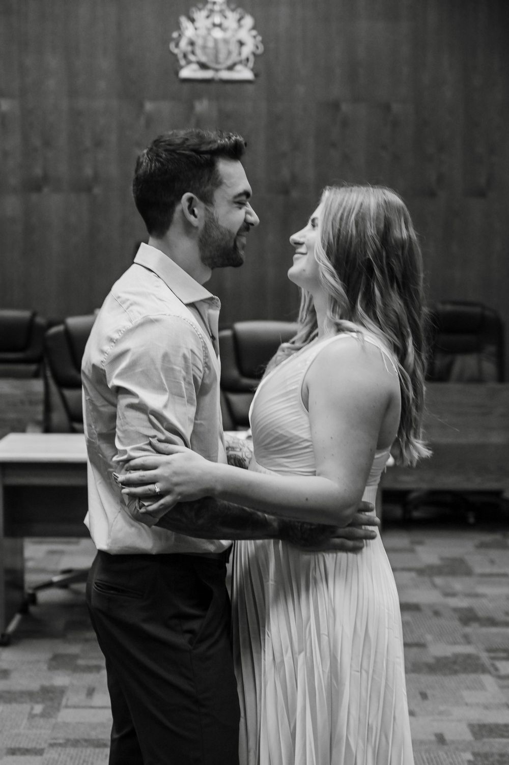 A joyful couple shares an intimate moment in a formal setting with a coat of arms visible in the background.