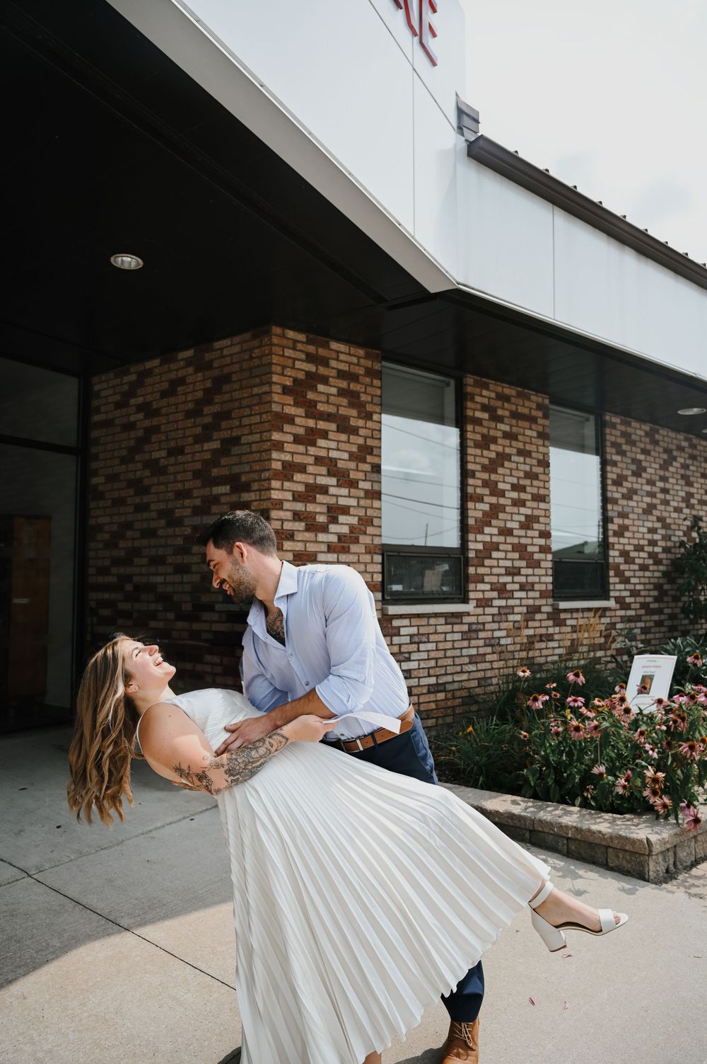 Couple shares romantic moment outside brick building as they dance and dip on the sidewalk.