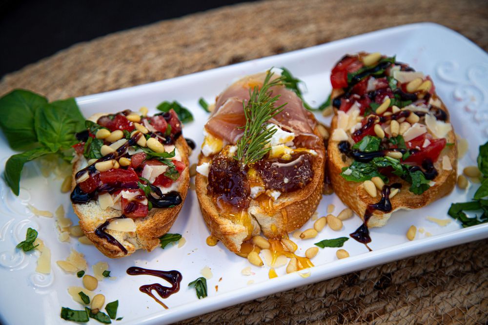 Gourmet bruschetta appetizers topped with colorful ingredients on a white serving plate.