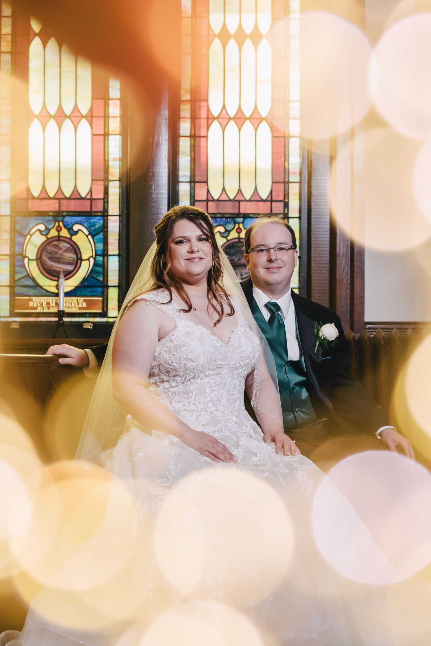 A wedding portrait with warm bokeh lights and stained glass windows creating a romantic atmosphere.