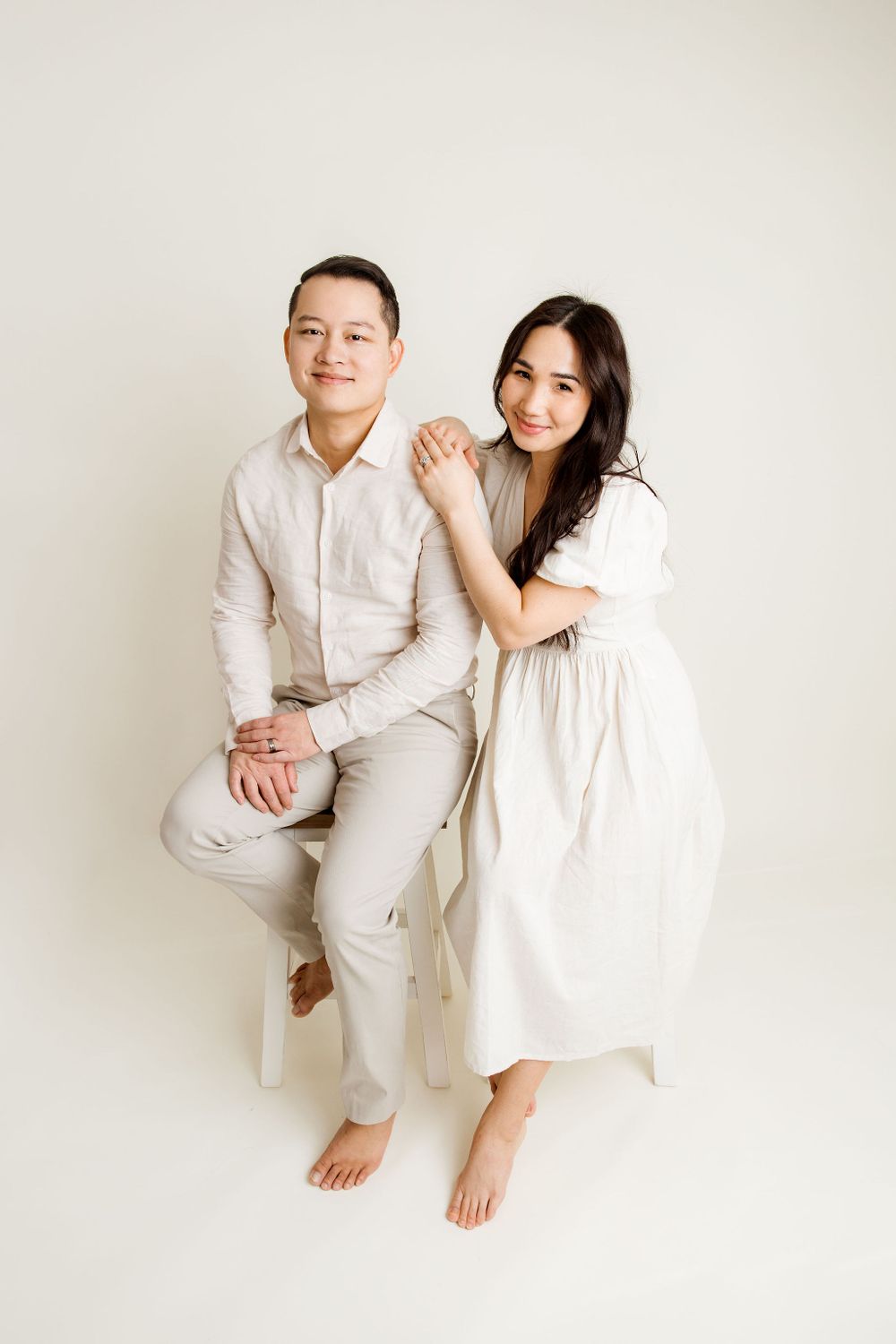Husband and wife sitting on two chairs during a studio family session