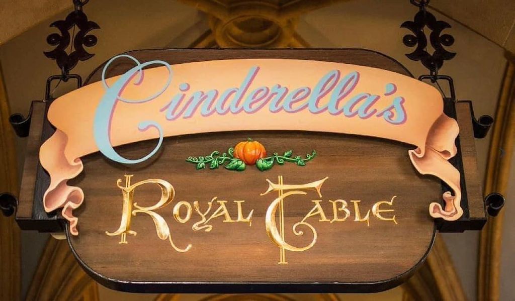 Carved wooden restaurant signs with elegant script lettering and decorative borders hang on a rustic wall.
