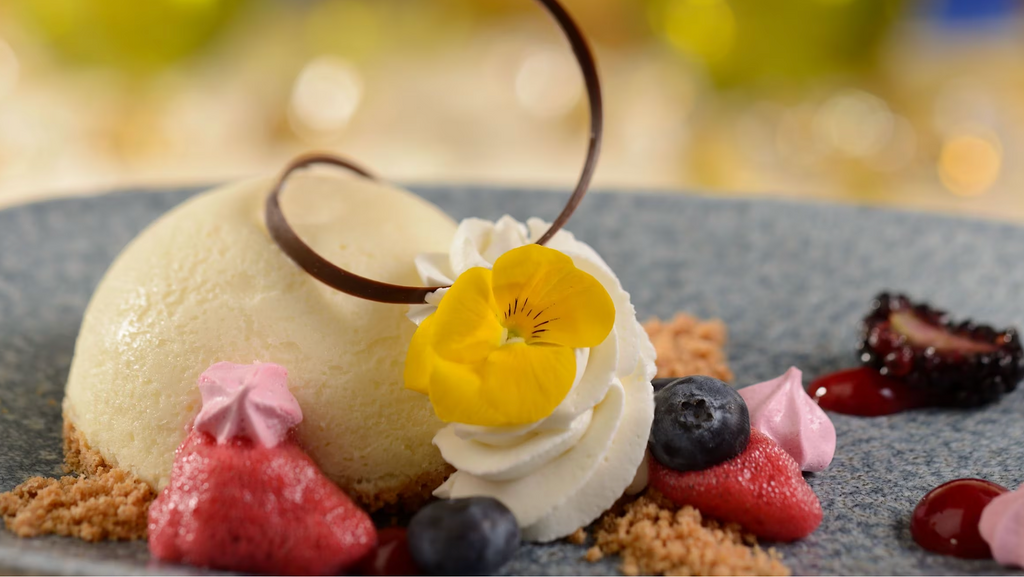 Elegant dessert plating featuring delicate pastries, colorful fruits, and artistic garnishes arranged in a row.