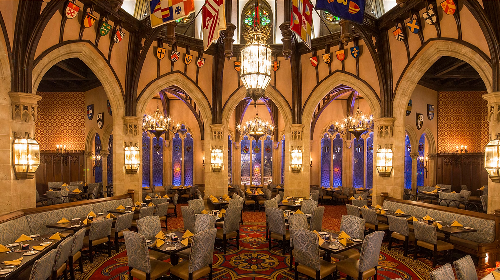 Elegant dining room at Disney's Be Our Guest Restaurant with Gothic arches, chandeliers and stained glass windows.