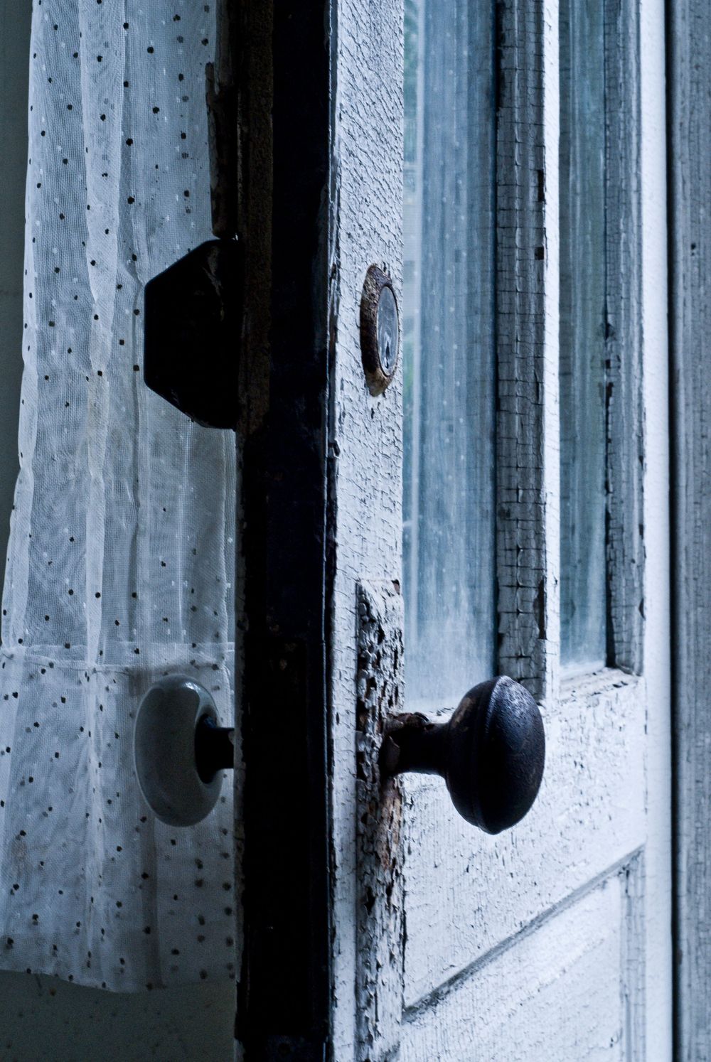 Vintage door knobs and lace curtain in soft moody lighting.