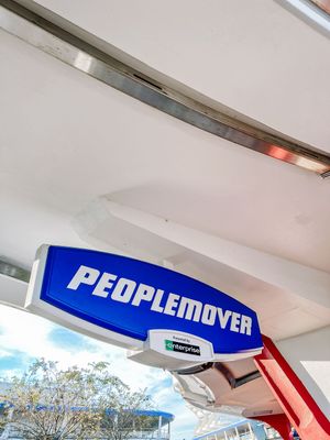 A close-up of a blue and red logo reading 'PEOPLE REMOVER' displayed on a white overhead structure outdoors.