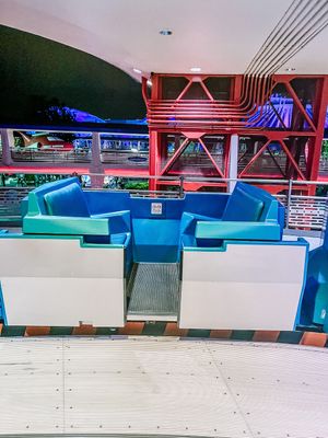 Interior bowling alley seating area with retro-style blue vinyl booths and red neon lighting accents.