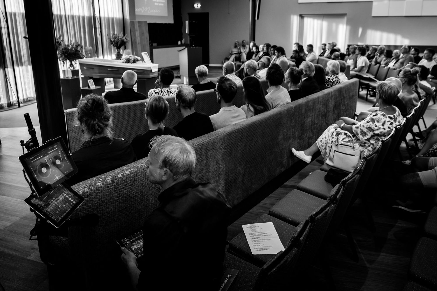 Black and white photo of attendees seated in rows at an indoor event or conference in a modern venue.
