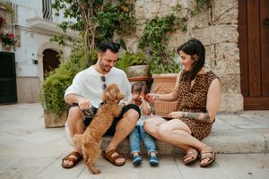 Young family with toddler and golden doodle dog sitting in a charming European courtyard.