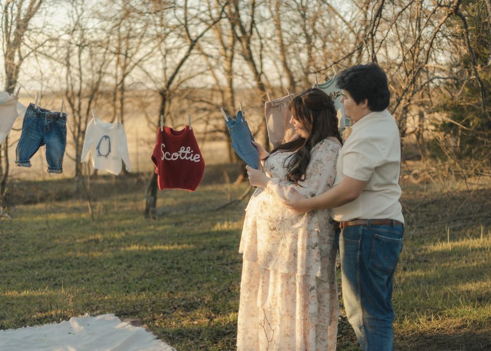 Expecting couple embracing near baby clothes on line during creative maternity photoshoot in Central Texas