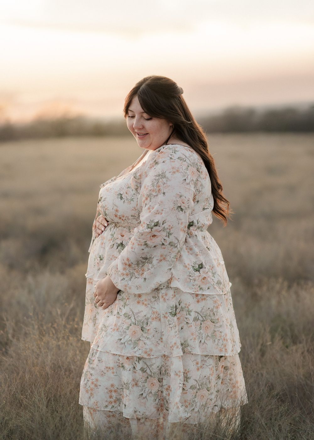 Expecting mother in flowing dress during outdoor maternity photos in Central Texas field at golden hour