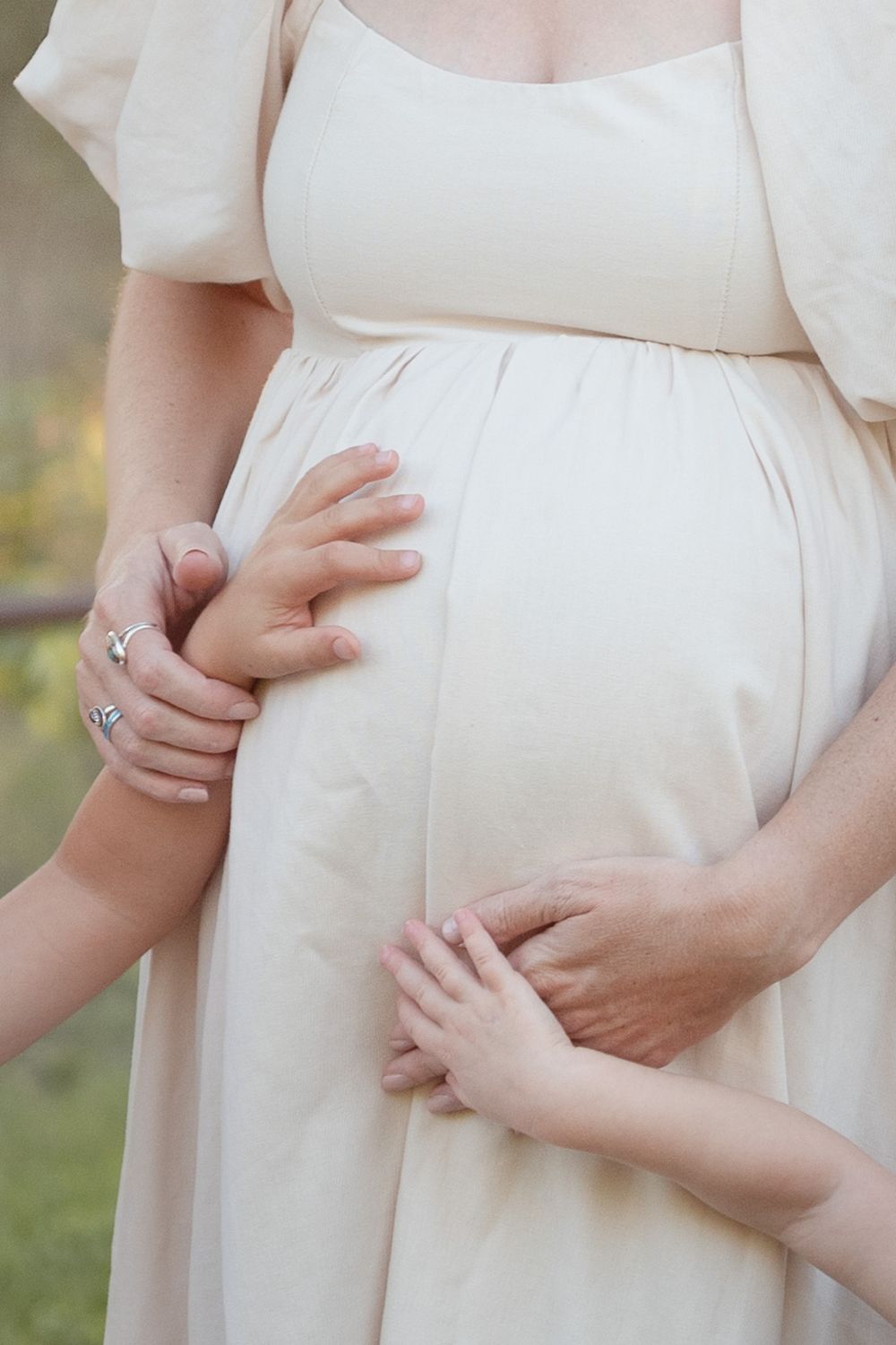Close-up of baby bump with parents hands during maternity photoshoot in Central Texas