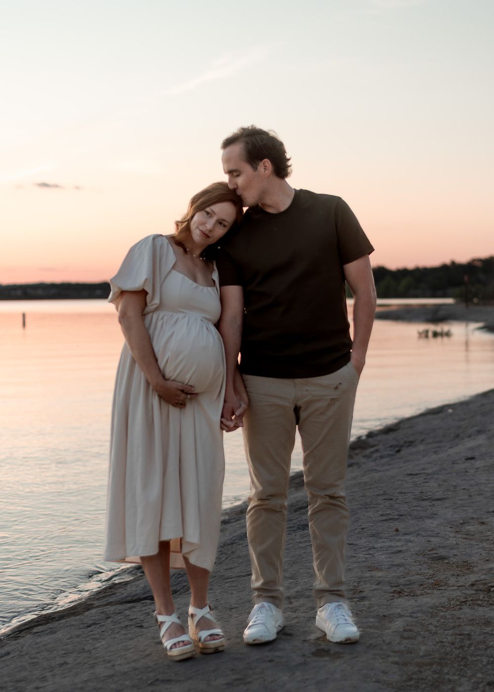 Pregnant couple standing by the water at sunset during romantic maternity session in Central Texas