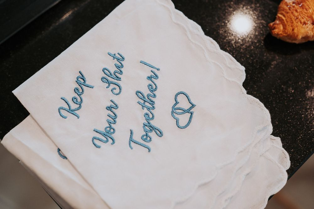 White embroidered handkerchief with blue cursive text reading Keep Your Shit Together with heart design.