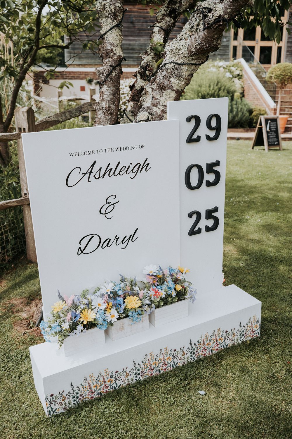 Elegant outdoor wedding welcome sign for Ashleigh and Daryl with floral decorations displaying the date 29 05 25.
