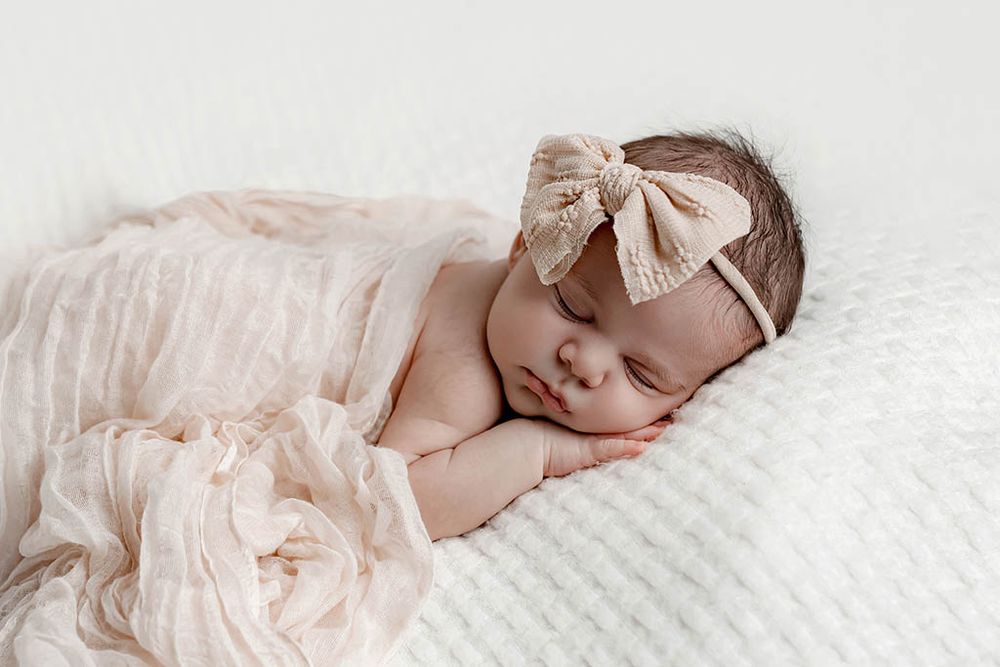 Sleeping newborn baby girl wrapped in soft pink blanket on white background by Winchester CA newborn photographer.