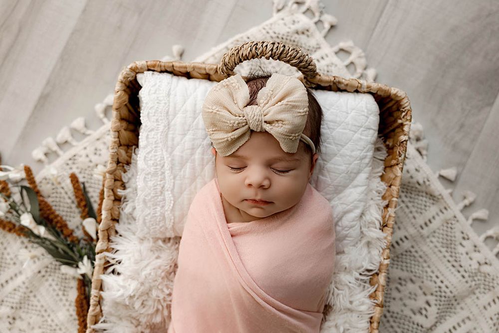 Winchester California newborn photographer photo of sleeping newborn baby girl in pink wrap and wicker basket prop.